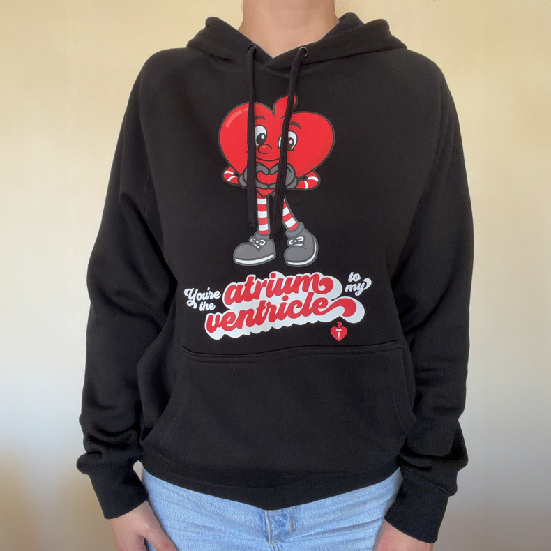 Person wearing a black hoodie with a cartoon heart design and text on a plain background