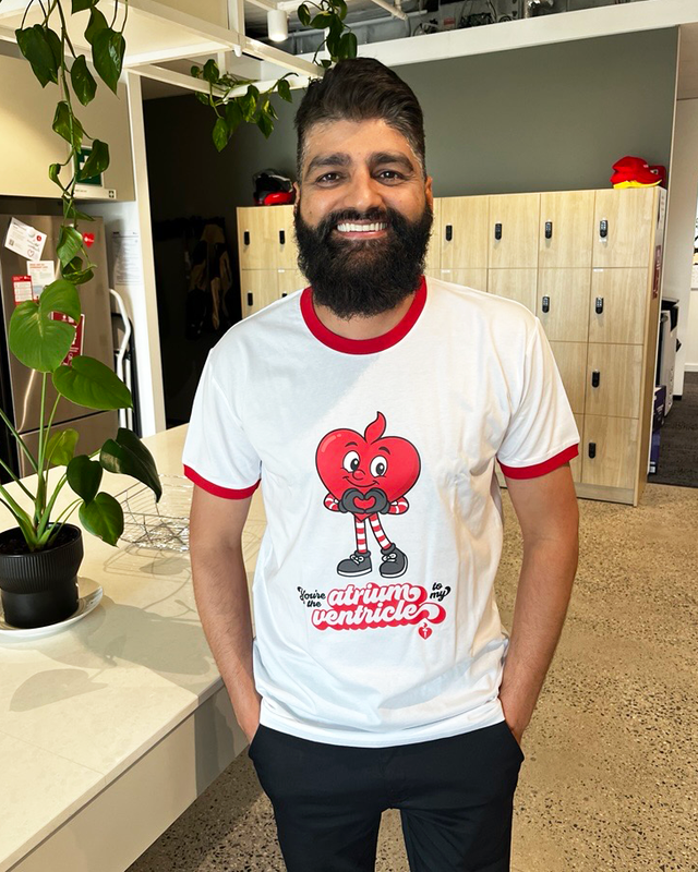 Man wearing a white t-shirt with a red and black design in an indoor setting