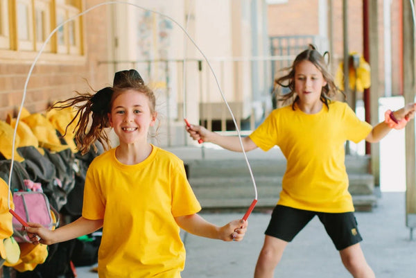 Two young children jumping with skipping ropes