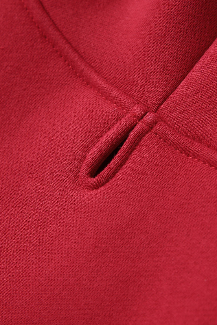 Close-up detail of a red fleece item showing a small front slit or keyhole opening.