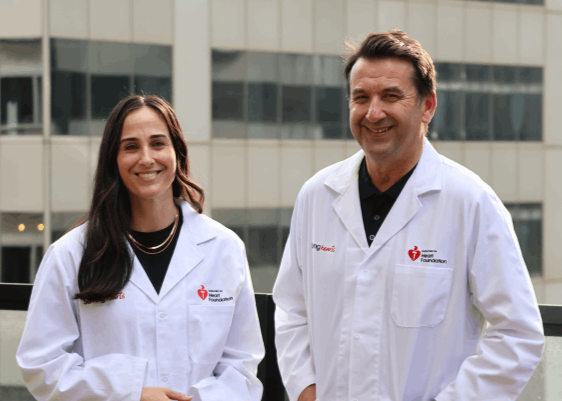 Two Heart Foundation funded researchers in white lab coats standing outdoors with a building in the background.