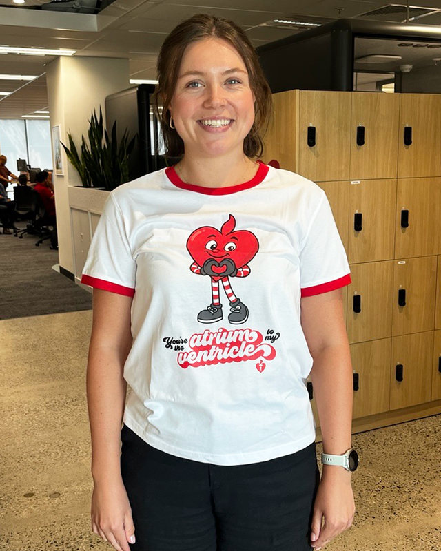 Person wearing a white t-shirt with a red and black graphic design in an office setting