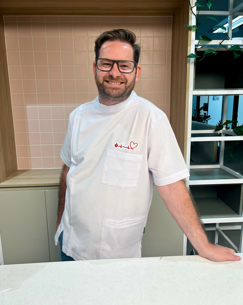 Man wearing a white pharmacy tunic with a logo in an indoor setting