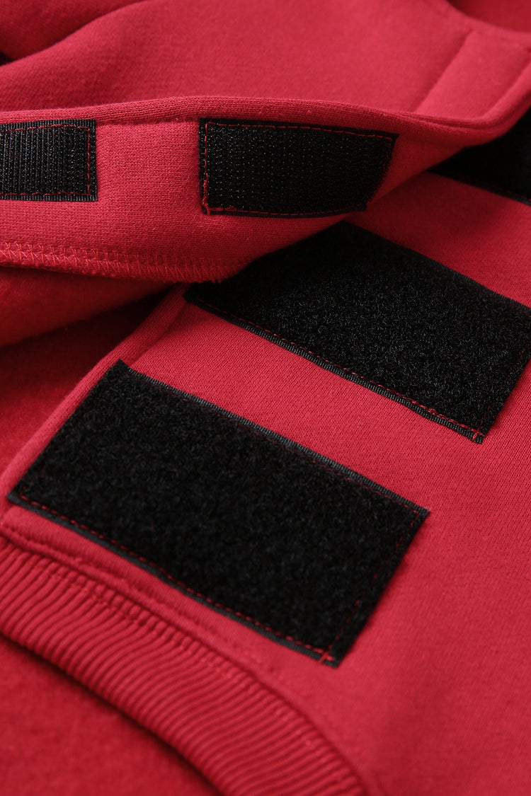 Close-up of a red fleece item with three black hook-and-loop velcro patches on the opening.