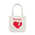 A cream tote bag with a red graphic on the front featuring the word 'Shocker' and a broken heart with a lightning bolt inside, shown against a light gray gradient.