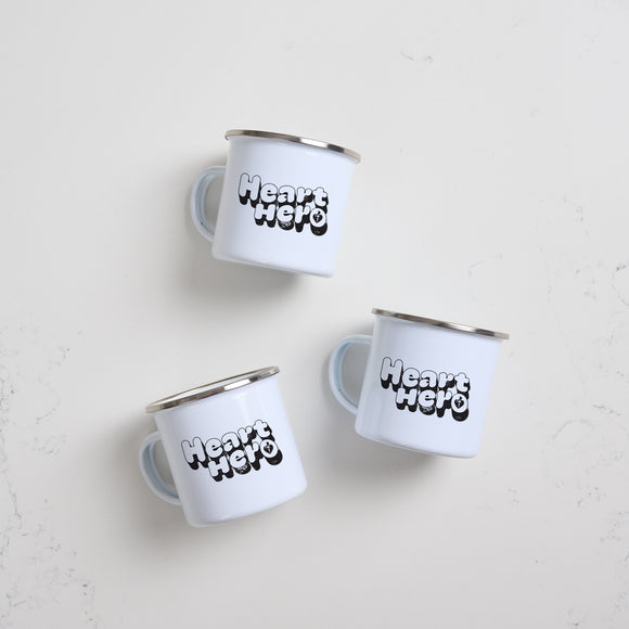 Heart Foundation white enamel mug with silver rim and Heart Hero print in  black vintage style font